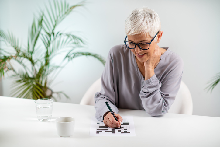 Vrouw zit aan tafel en maakt een puzzel op een witte tafel