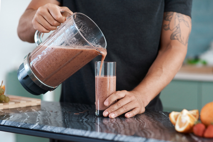 Man schenkt eiwit shake in glas